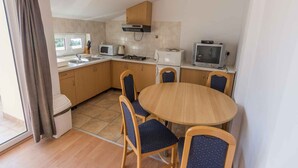 A compact kitchen with a dining area, featuring a microwave, toaster, and a small television. - Holiday apartment with sea view (Biograd na Moru)