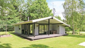 Une petite cabane d’un seul étage, dotée d’un porche couvert, d’une antenne parabolique et d’un espace barbecue.
