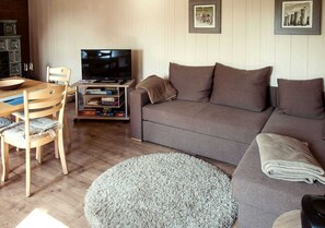 Uma sala de estar com sofá, televisão, mesa de centro e estante.