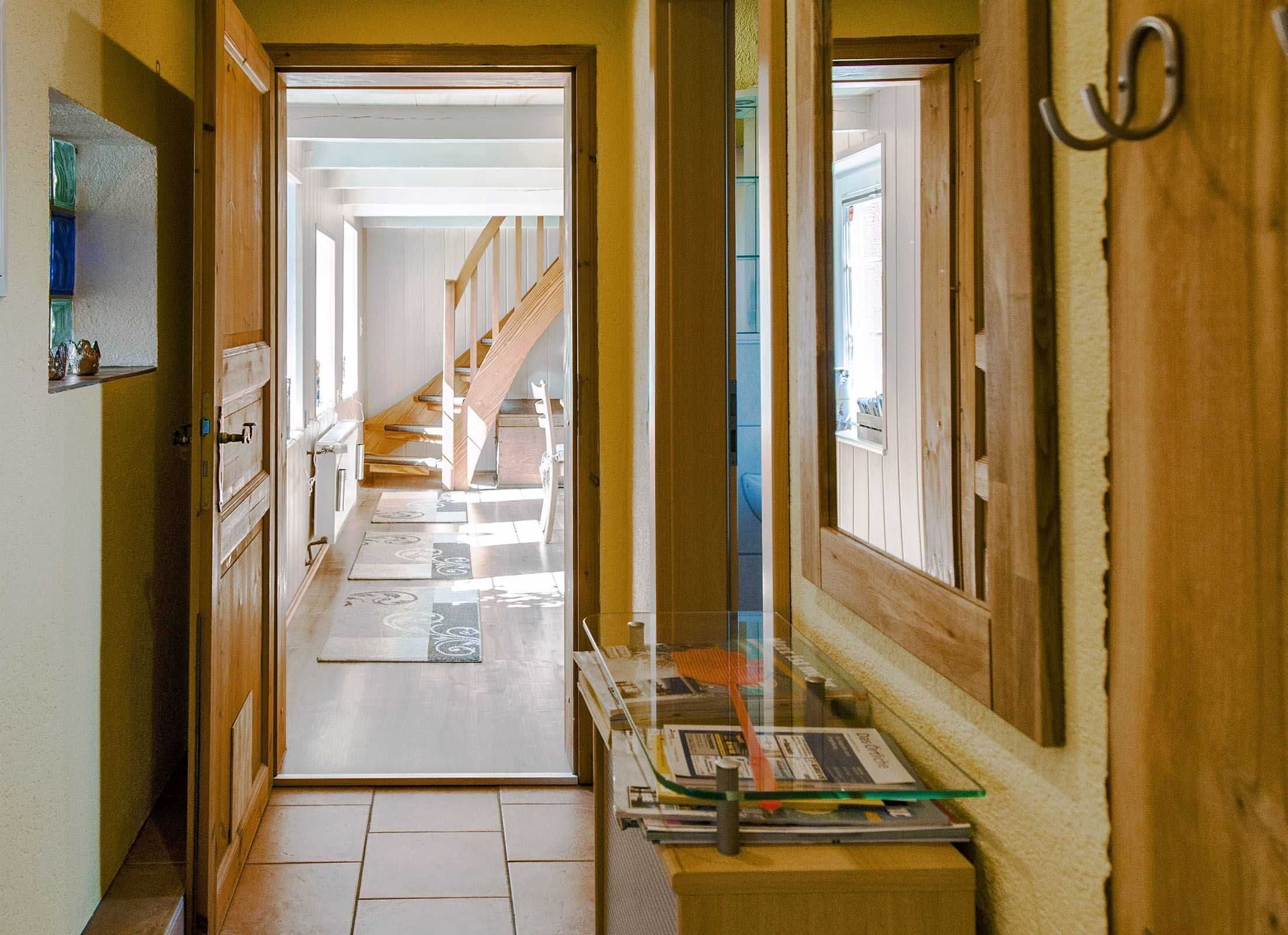 A hallway with wooden floors, a glass display case, and a staircase leading to another room.