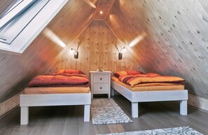 Quarto de sótão acolhedor, com duas camas, um claraboia e paredes de madeira.