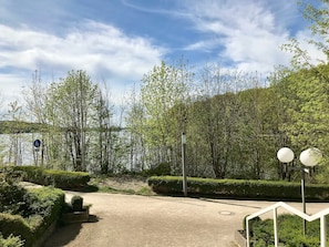 Un parque con un sendero de tierra, arbustos cuidados y árboles.