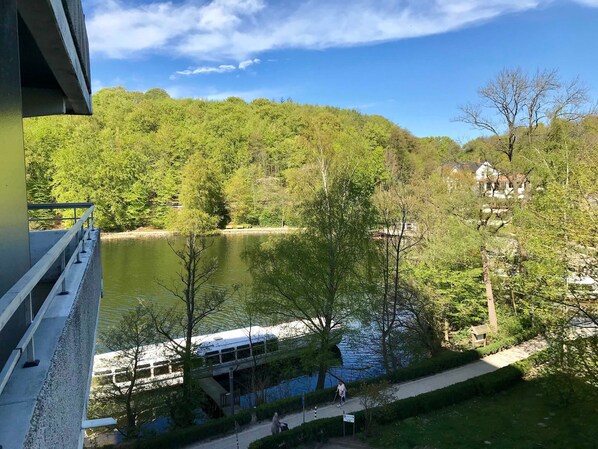 A view of a river with a bridge and a boat. There are trees and a building in the background.