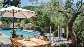 A wooden pool table with an umbrella, surrounded by potted plants and a pool. - Nice apartment in La Valette du Var (La Valette du Var)