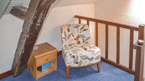A small room with a wooden chair, a wooden nightstand, and a blue carpet.