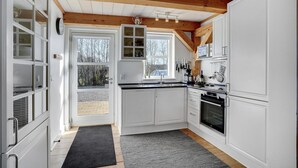 A modern kitchen with white cabinets, a black countertop, and a wooden ceiling. - Cozy home in Blåvand with WiFi (Blåvand)
