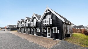 A row of black wooden buildings with white trim, each featuring a balcony and a door. - Cozy home in Blåvand with WiFi (Blåvand)