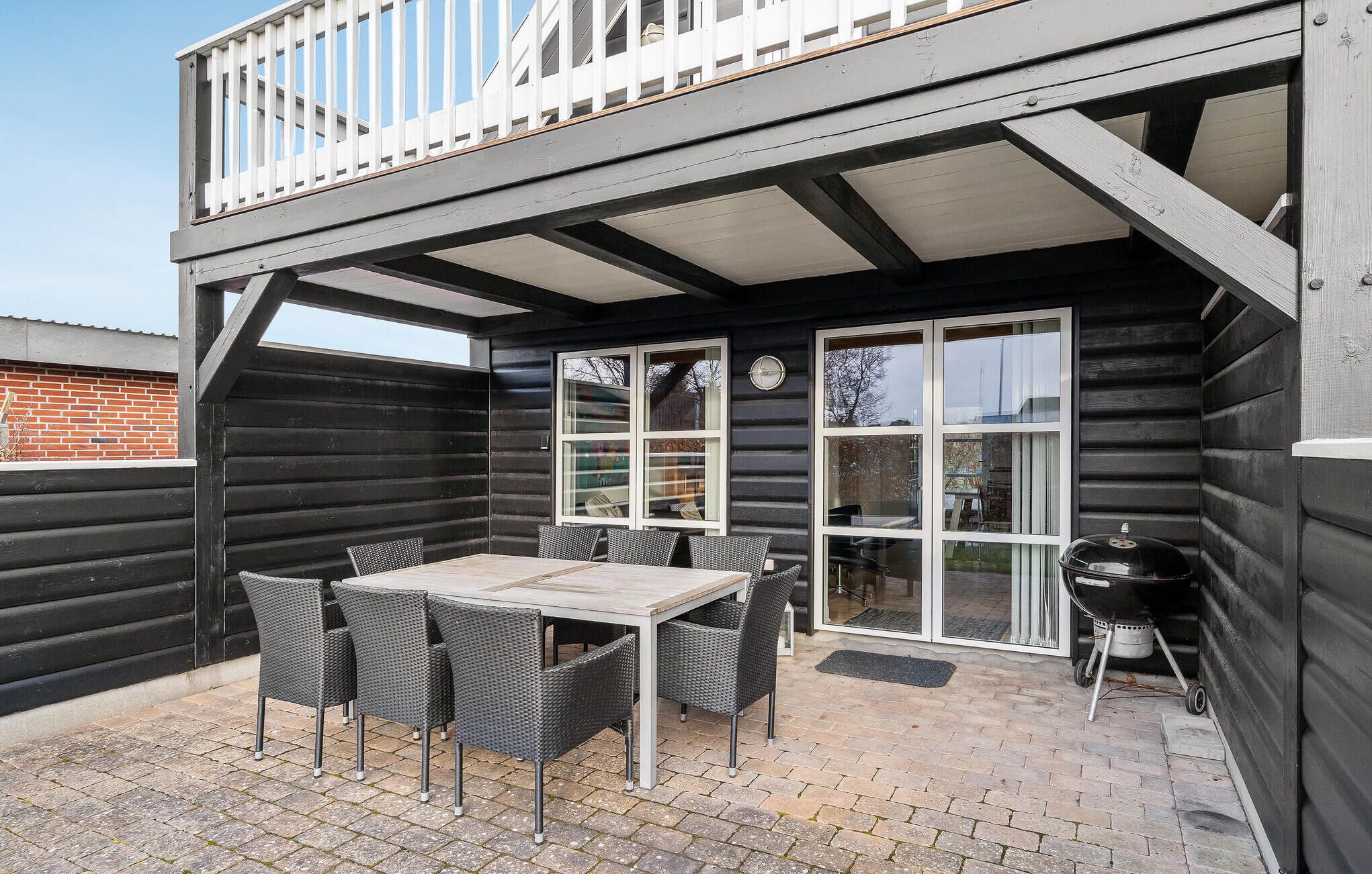 A patio with a table and chairs, a grill, and a view of the surrounding area.