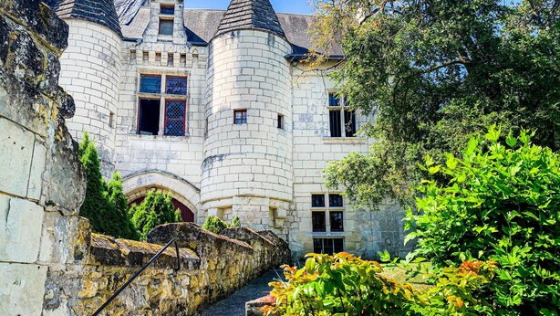 A historic stone building with a turreted tower, arched entrance, and a narrow pathway leading to the main entrance.
