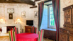 A room with a fireplace, a television, a window with curtains, and a wooden cabinet.