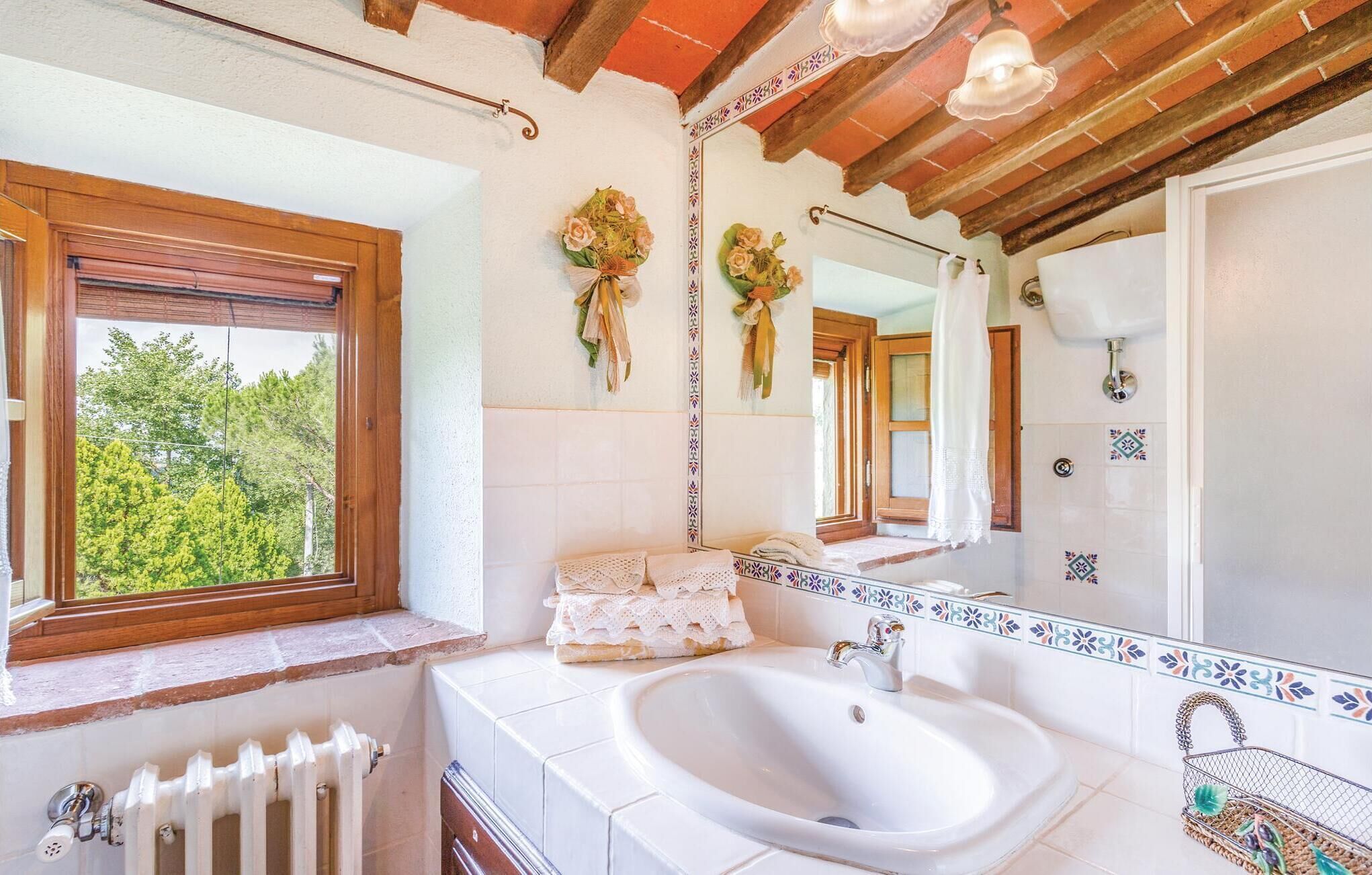 Een badkamer met een witte wasbak, een houten raam en een spiegel met decoratieve rand.