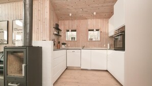 A modern kitchen with white cabinets, a built-in stove, and wooden flooring. - 3 bedroom beautiful home in Fanø (Fanø)