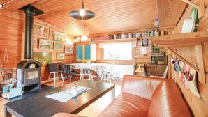 Ein gemütliches Blockhäuschen mit Holzeinrichtung, Kamin, Essbereich und einer Couch.