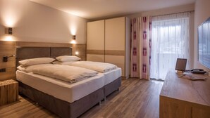 Ein Schlafzimmer mit Bett, Nachttischen, einem Schreibtisch mit Computer und einem Fenster mit Vorhängen.