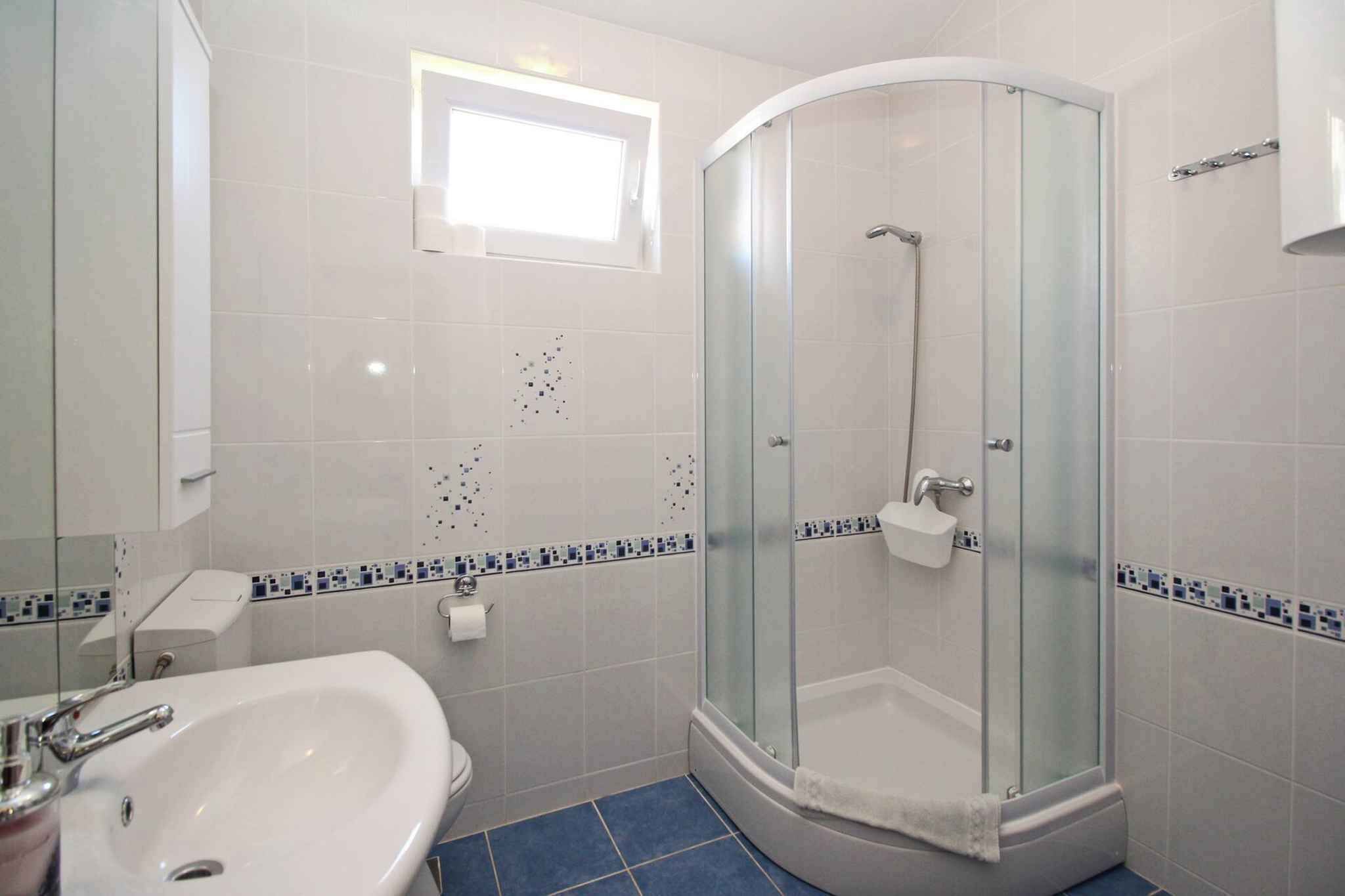 A bathroom with a glass-enclosed shower, a sink, and a toilet.