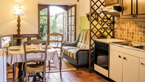 Une cuisine chaleureuse avec une table à manger, des chaises, un canapé et un poêle.