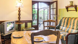 Un coin repas accueillant avec un téléviseur, une table dressée pour deux personnes et un canapé.