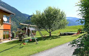 A house with a swing set, a tree, and a view of mountains.