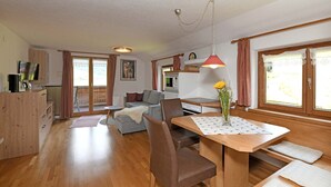 Eine moderne Küche mit Essbereich, Holzmöbeln und großen Fenstern.