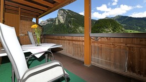 Ein überdachter Außenbereich zum Sitzen mit Tisch, Stühlen und einem Blumenstrauß.