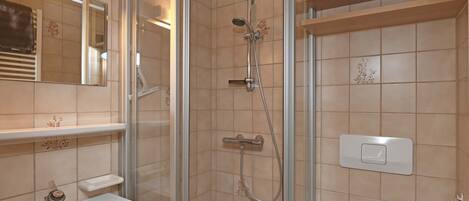 A bathroom with a glass-enclosed shower, a sink, and a toilet.