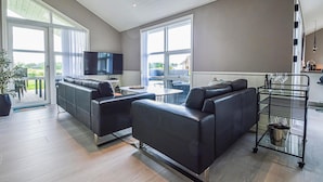 Un salon moderne comprenant un canapé, un téléviseur et un coin repas avec une table et des chaises.