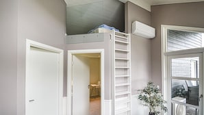 Une pièce avec un lit superposé, une échelle, une porte, une fenêtre et un ventilateur.