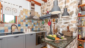 Eine Küche mit Steinwand, Spüle, Herd und einer Arbeitsplatte mit Obstschale.