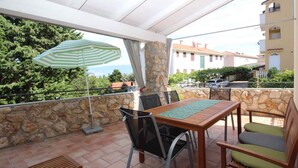 A terrace with a table and chairs, a striped umbrella, and a stone wall.