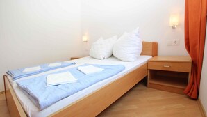 A single bed with a wooden frame, a bedside table, and a nightstand.