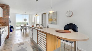 Een moderne keuken met een groot eiland, een eethoek en uitzicht op de omgeving.