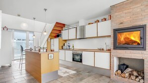 Een moderne keuken met een centraal eiland, een inbouwoven en een open haard.