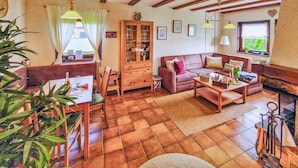 A cozy living room with a wooden floor, a sofa, a coffee table, and a dining area with a table and chairs.