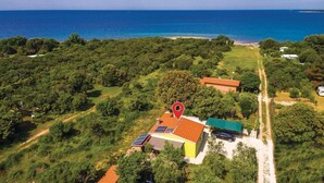 An aerial view of a property with a house, solar panels, and a red location marker.