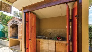 A compact kitchen with a brick oven, a sink, and a countertop with vegetables.