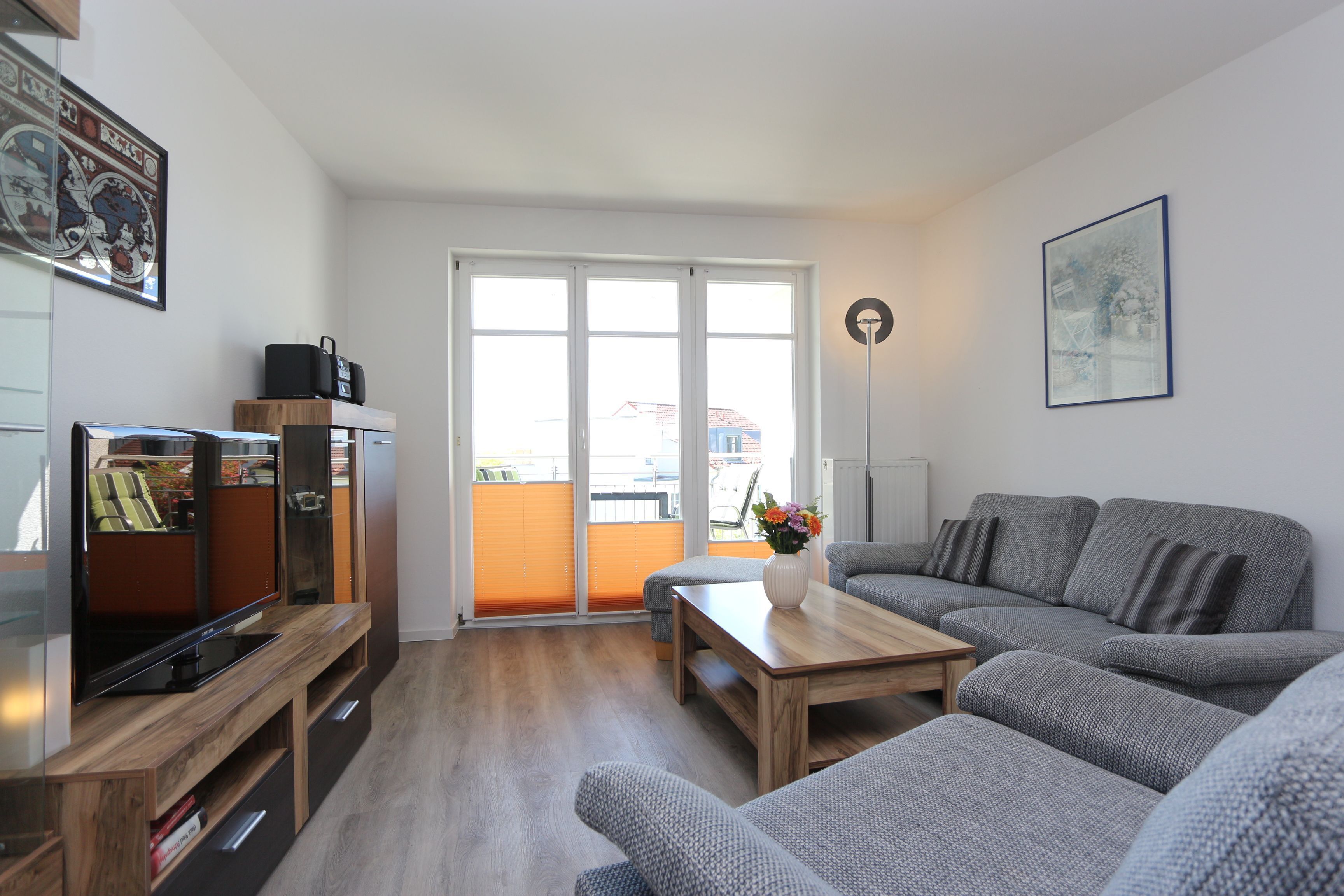 Una sala de estar moderna con un sofá gris, una mesa de centro de madera y un televisor de pantalla plana sobre un mueble de madera.