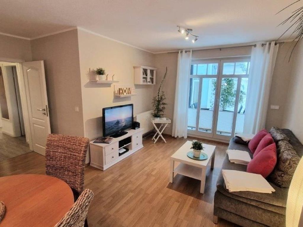 A modern living room with a flat-screen TV, a dining table, and a sofa.