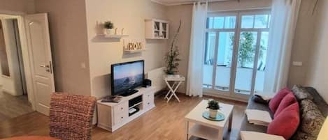 A modern living room with a flat-screen TV, a dining table, and a sofa.
