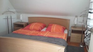 A bedroom with a wooden bed, two bedside tables, and a nightstand.