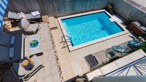 A rooftop pool area with lounge chairs, a table with a decorative umbrella, and a small garden with plants. - Stunning home in Sv.Filip i Jakov (Sv.Filip i Jakov)