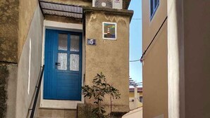 Une ruelle étroite avec une porte bleue et un escalier menant à un immeuble.