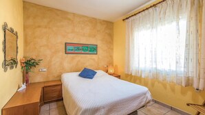 Un dormitorio con una cama, una mesita de noche, una lámpara, un espejo y un cuadro en la pared.