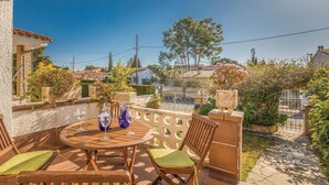 Un patio al aire libre con una mesa y sillas de madera redonda, rodeado de un muro de piedra y plantas en macetas.