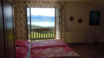 A bedroom with a bed, a view of a lake, a radiator, and a chair.