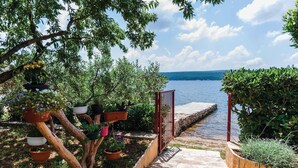 Un jardin agrémenté de plantes en pot et d’un chemin de pierre menant à un plan d’eau.