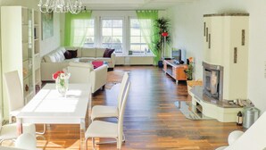 Een moderne woonkamer met een bank, eettafel, stoelen, een televisie en een open haard.