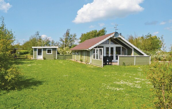 Guest accommodations feature large windows and a serene natural setting with a well-maintained lawn and wildflowers.