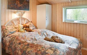 Cozy bedroom with a large window and a comfortable bed, featuring a floral-patterned bedspread and a nearby wardrobe.