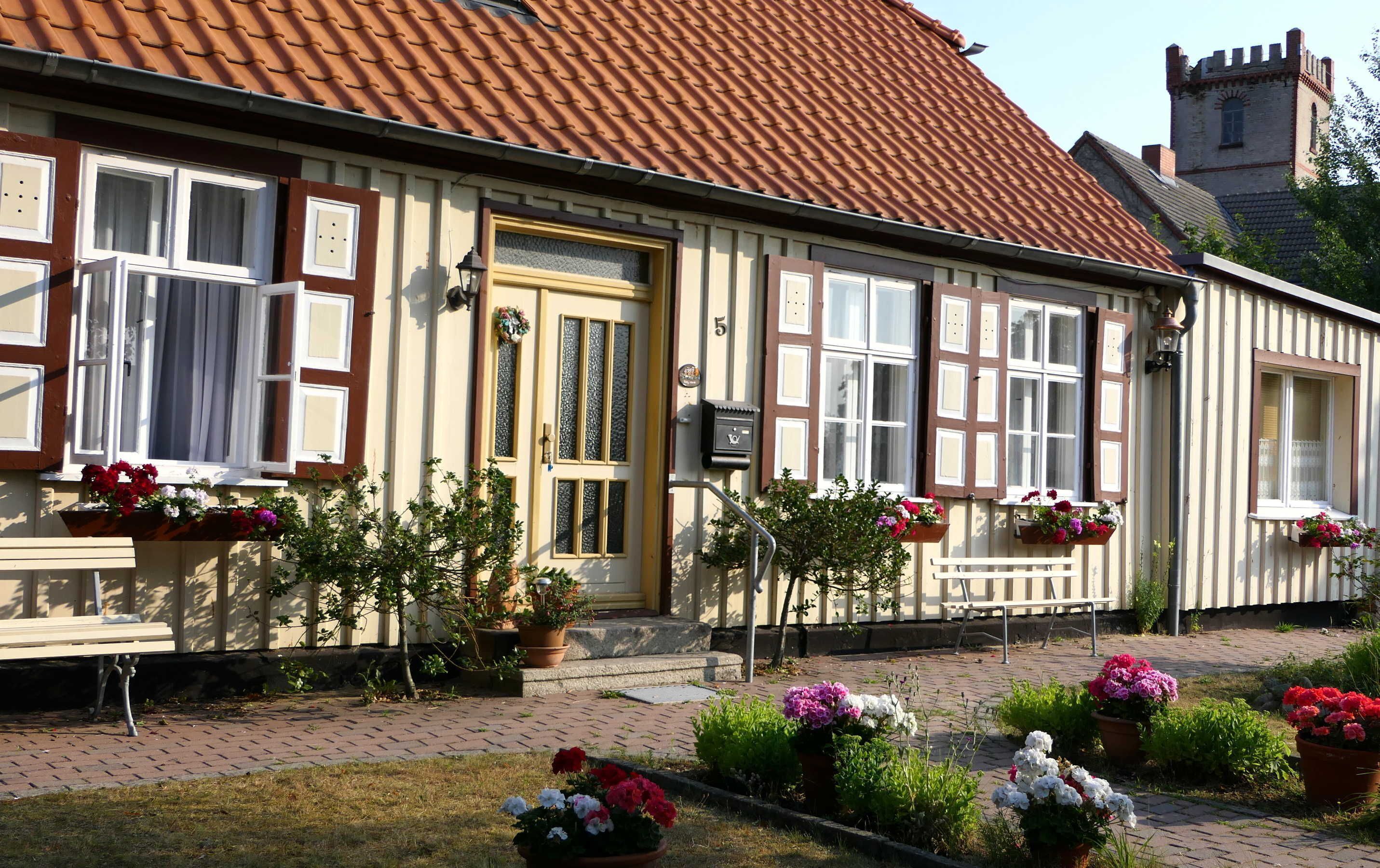 A traditional European-style building with a tiled roof, multiple windows with shutters, and flower boxes on the windowsills.