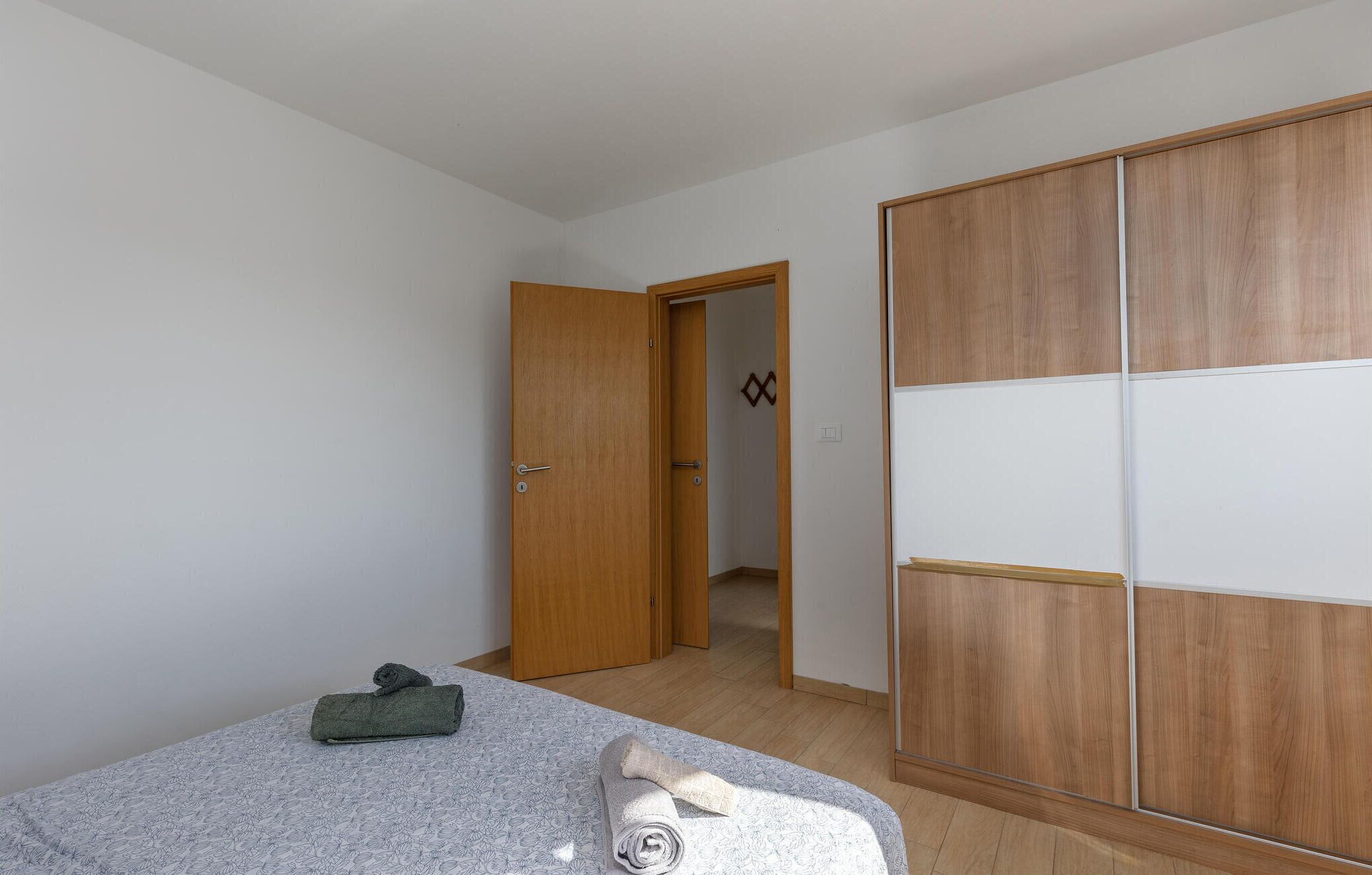 Une chambre à coucher avec un lit, une armoire en bois et une porte donnant sur une autre pièce.